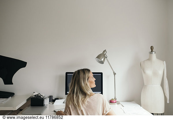 Rear view of female design professional using computer at home