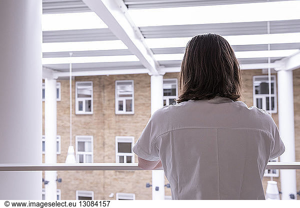 Rear view of female doctor standing by railing in hospital