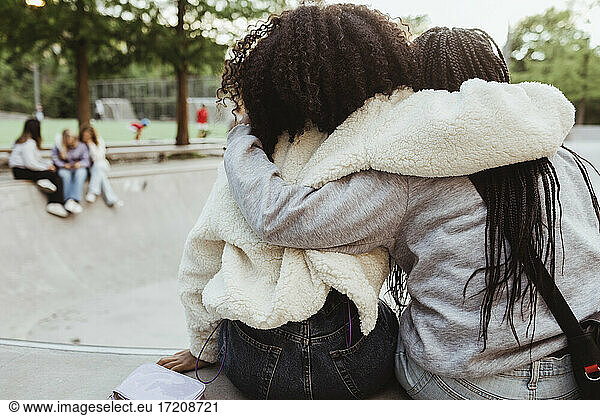 Rear view of female friends with arms around at skateboard park