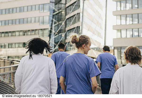 Rear view of female healthcare colleagues walking towards hospital