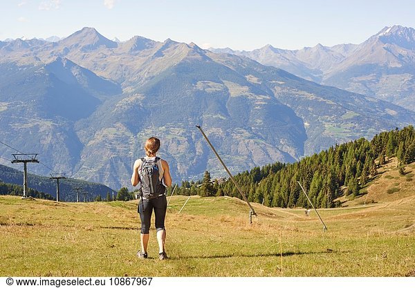 Rear view of female hiker standing looking out over mountain landscape  Aosta Valley  Aosta  Italy