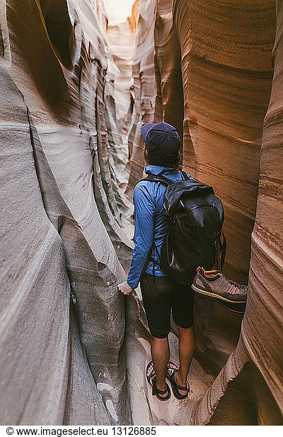 Rear view of female hiker with backpack standing amidst narrow canyons