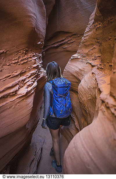 Rear view of female hiker with backpack walking amidst canyons
