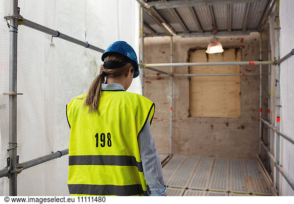 Rear view of female manager walking at construction site