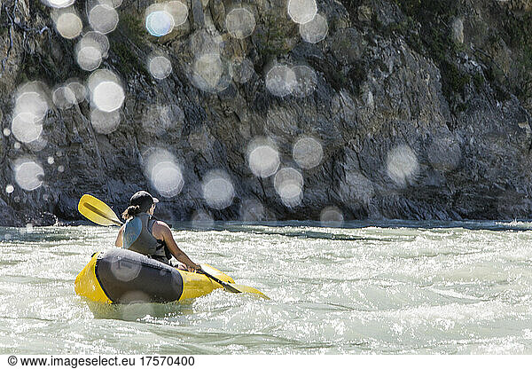 Rear view of fit active woman paddling the Kootney River.