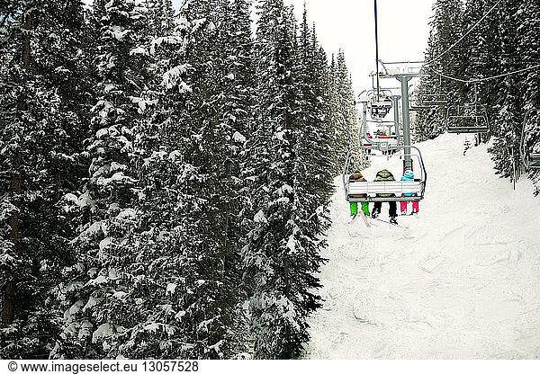 Rear view of friends sitting in ski lift