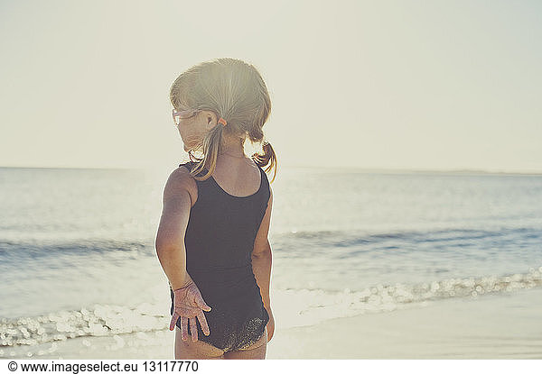 Rear view of girl in swimwear standing on beach