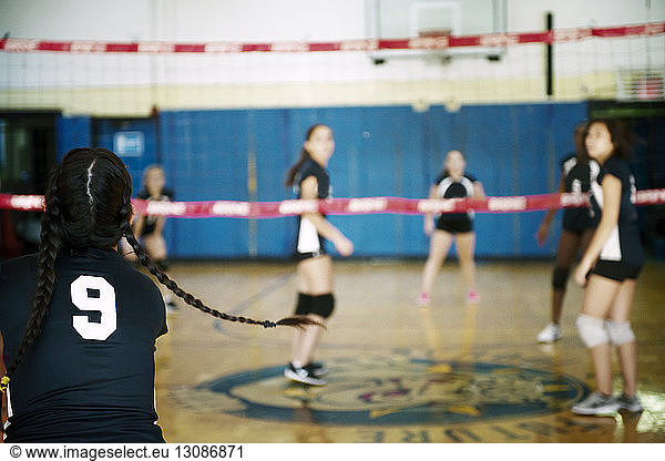 Rear view of girl playing volleyball in court