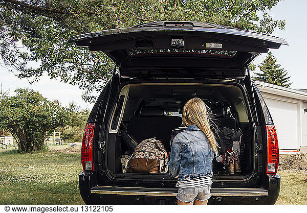 Rear view of girl standing by car trunk