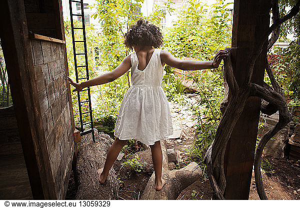 Rear view of girl standing on tree trunks