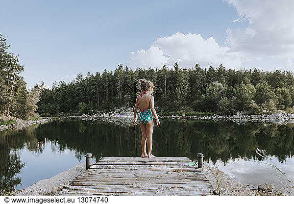 Rear view of girl swimwear standing on jetty steps by lake