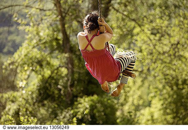 Rear view of girl swing on rope
