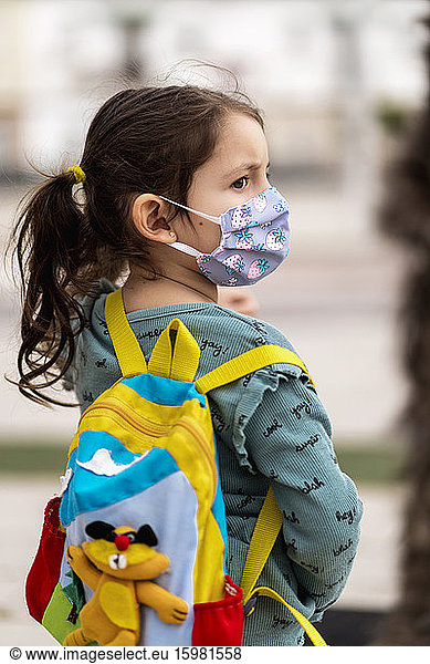 Rear view of girl with mask and backpack