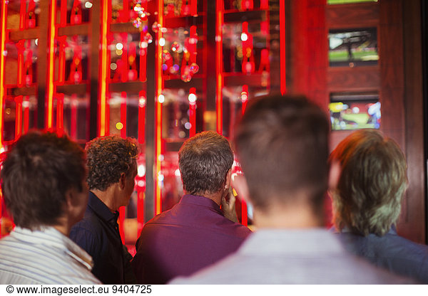 Rear view of group of men watching TV in bar