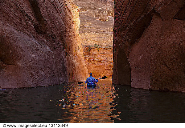Rear view of hiker kayaking on Lake Powell amidst canyons