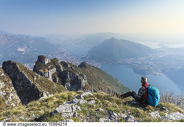 Rear view of hiker sitting on mountaintop  Orobie Alps  Lecco  Italy