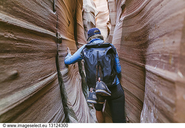 Rear view of hiker with backpack canyoneering amidst narrow canyons