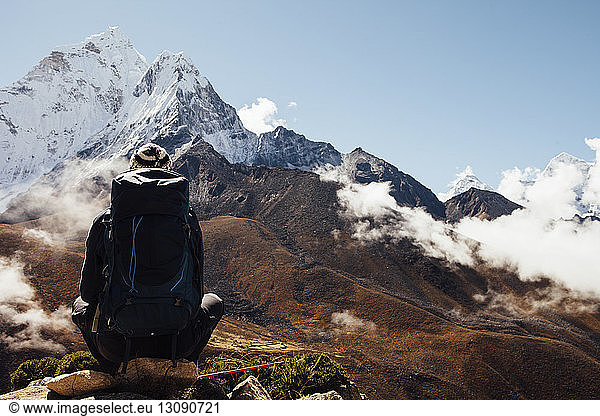 Rear view of hiker with backpack sitting on mountain blue sky at Sagarmatha National Park