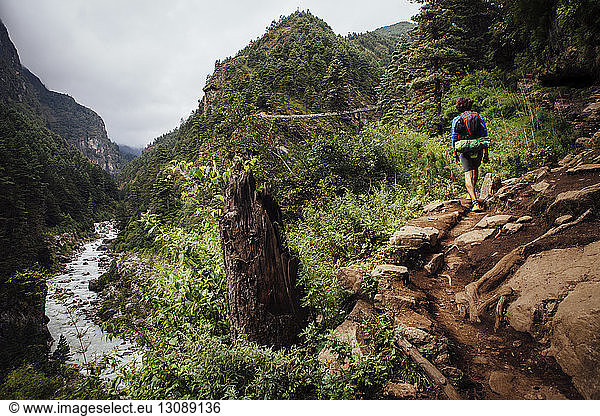 Rear view of hiker with backpack walking on mountain at Sagarmatha National Park