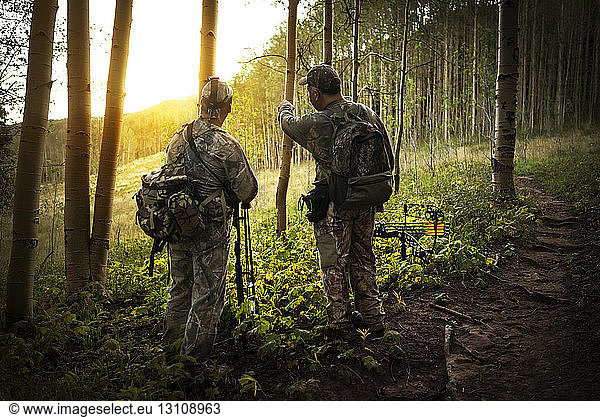 Rear view of hunters discussing in forest