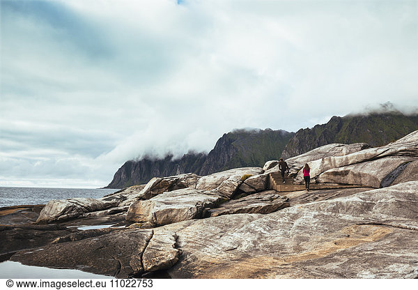 Rear view of man and woman walking on rocks at island