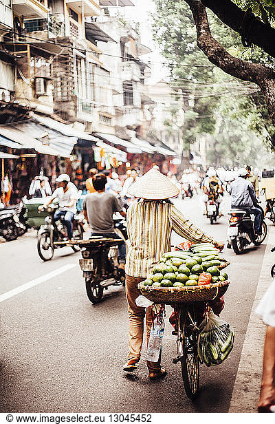Rear view of man carrying fruits and vegetables in basket on bicycle at market