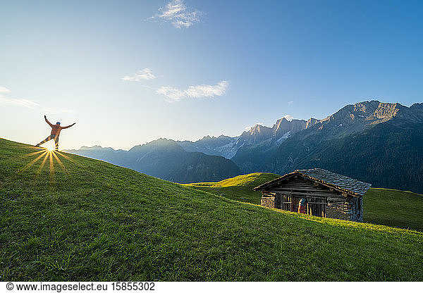 Rear view of man exulting at dawn  Tombal  Soglio  Switzerland