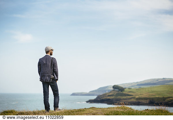 Rear view of man looking at view while standing on hill
