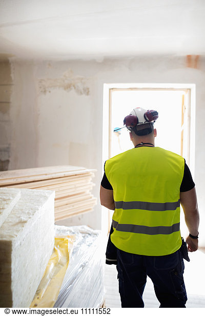 Rear view of man standing in brightly lit room at construction site