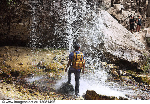 Rear view of man standing under waterfall at Hanging Lake