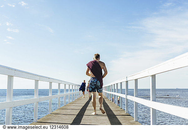 Rear view of man walking on pier