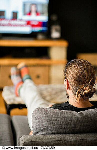 Rear view of man watching TV at home