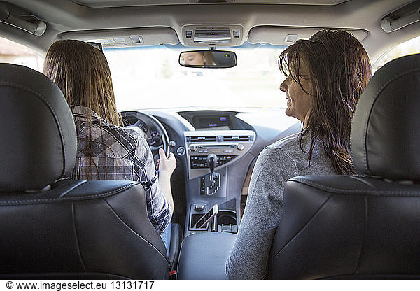 Rear view of mother and daughter travelling in car