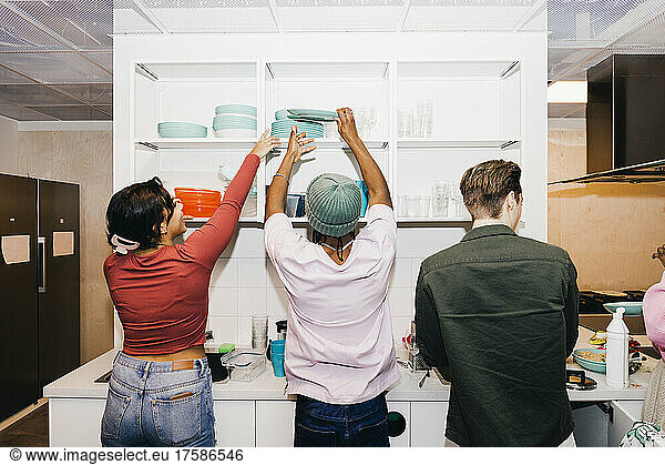 Rear view of multiracial male and female students in kitchen at college dorm