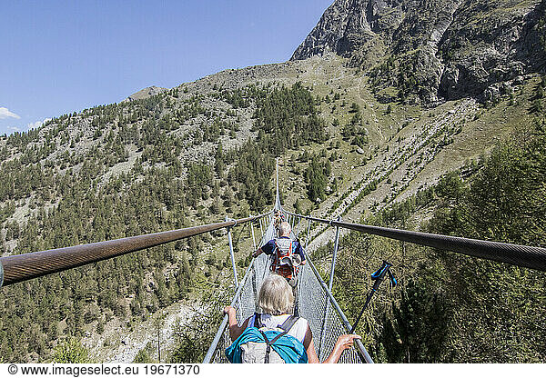 Rear view of people walking on Worlds Longest Pedestrian Suspension Bridge during daytime  Randa  Wallis  Switzerland