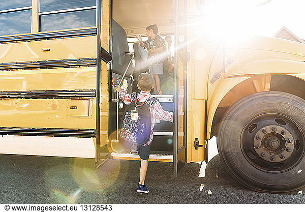 Rear view of schoolboy stepping on bus
