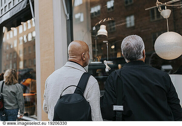 Rear view of senior male friends doing window shopping at street