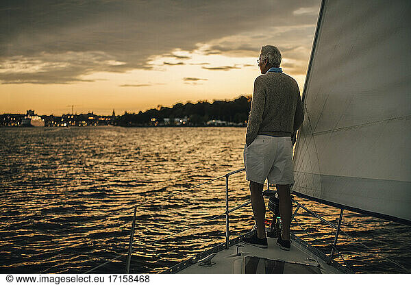 Rear view of senior man looking at sea during sunset