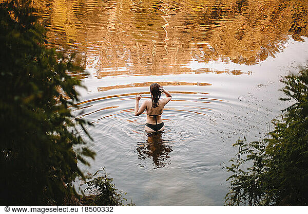 Rear view of sensual woman standing in lake