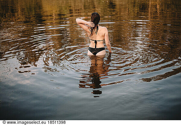 Rear view of sensual woman standing in water