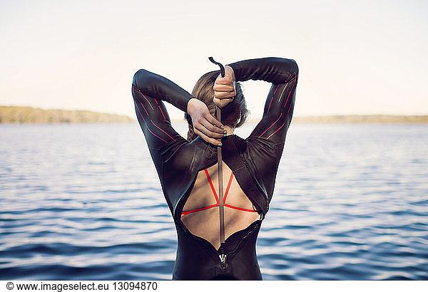 Rear view of swimmer wearing wetsuit at lakeshore