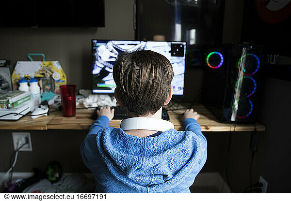 Rear View of Teen Boy Playing Gaming Computer on a Messy Desk