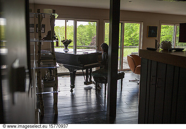 Rear View of Teen Girl Playing Piano in Residential Home