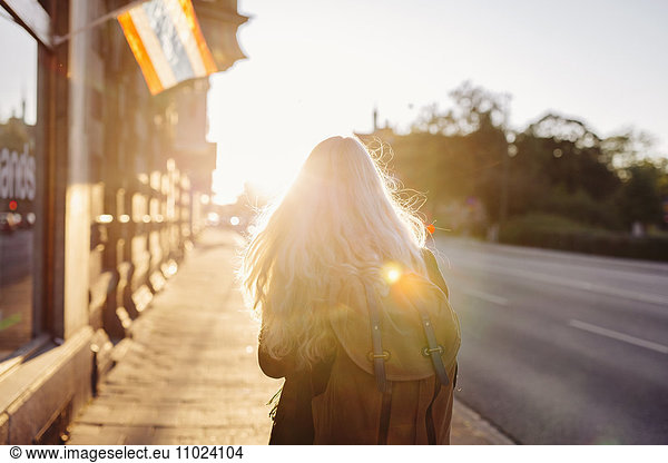Rear view of teenage girl walking on footpath during sunset