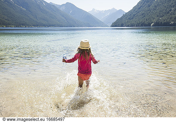 Rear view of toddler girl running into Chilliwack Lake  B.C.  Canada.