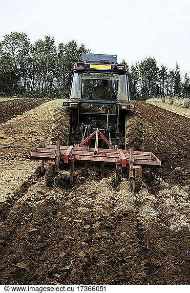 Rear view of tractor plowing a field on a farm.