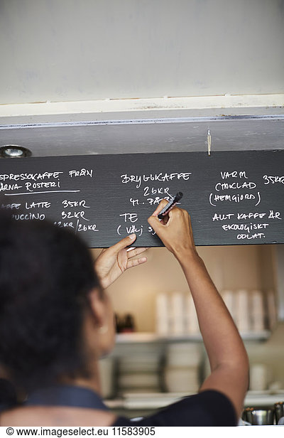 Rear view of waitress writing on menu at cafe