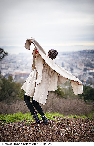 Rear view of woman holding jacket while enjoying on mountain top
