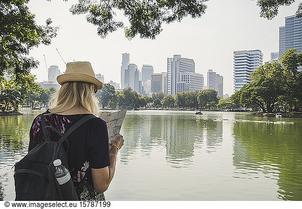 Rear view of woman looking at map in Lumphini Park  Bangkok  Thailand