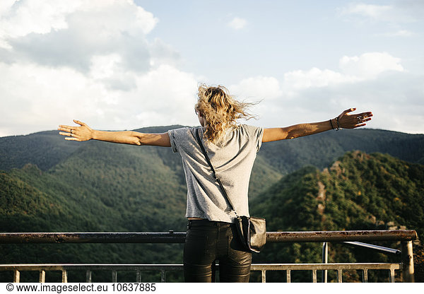 Rear view of woman looking at mountains with arms outstretched